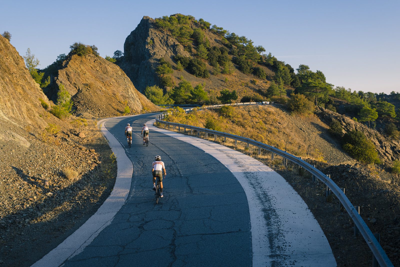 Three riders climbing toward a rocky crag in golden evening light near Lefkara